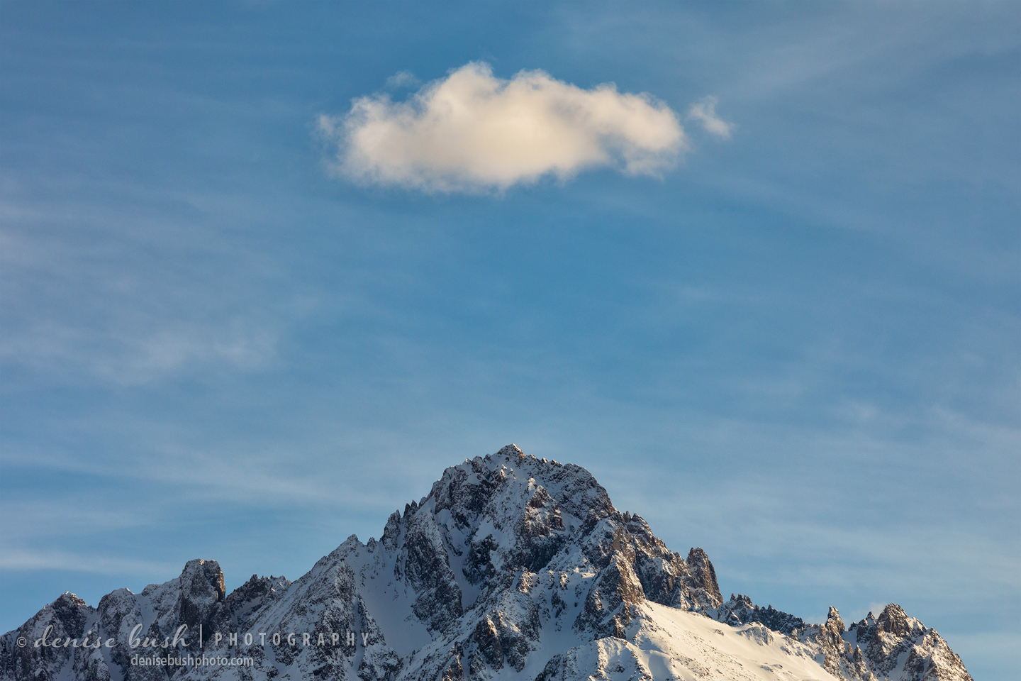 A cloud drifts over the peak of Mount Sneffels as if to dot it!